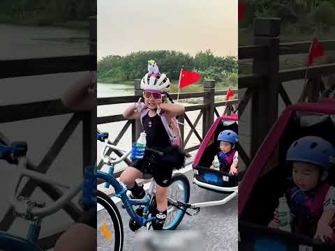 Little girl riding her bicycle fast with her younger brother.