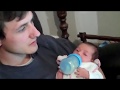 Bébé qui boit biberon dans bras de papa