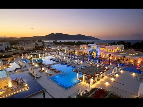 Anemos Luxury Grand Resort Poolbereich bei Dämmerung mit Palmen und beleuchteten Gebäuden