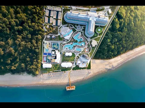 Ethno Belek Hotel mit Meerblick, Gebäude mit vielen Fenstern, Parkplätze und Palmen vor dem Hotel.