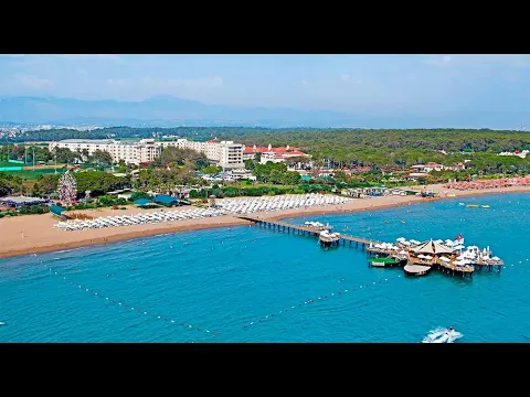 Luftaufnahme des Sueno Hotels Beach Side mit vielen Liegen am Strand und einem Steg im Meer