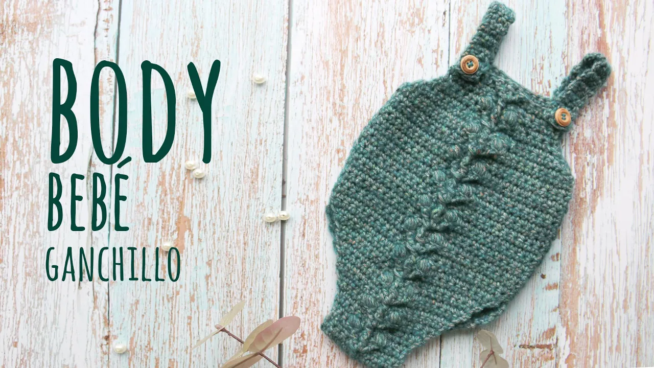 Body verde de bebé a crochet con una trenza central, tirantes abotonados y textura tupida.