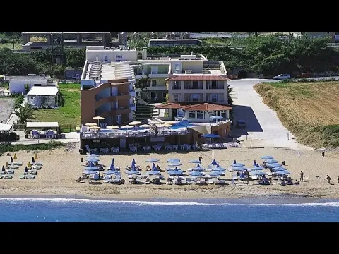 Luftaufnahme des Dedalos Beach Hotels mit Pool und vielen Sonnenschirmen am Strand