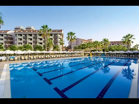 Außenpool des Primasol Hane Family Resort Hotels mit Sonnenliegen und Palmen.