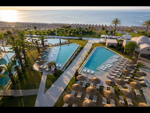 Luftaufnahme des Pegasos Deluxe Beach Hotel Resorts mit mehreren Swimmingpools, Grünflächen und einer Bergkulisse.