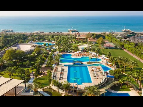 Ein Swimmingpool des Sherwood Exclusive Lara Hotels mit einem blauen Wasserspiegel und einer Brücke.