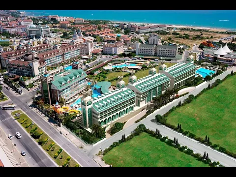 Luftaufnahme des Well Palace Side Hotels mit mehreren Pools und Meerblick.