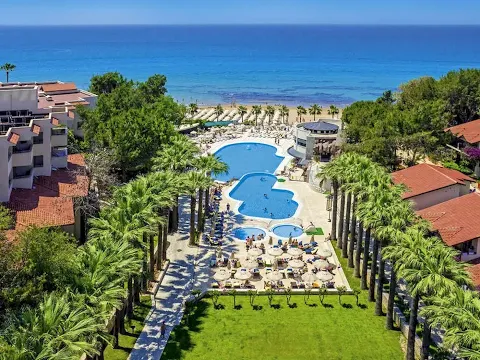 Luftaufnahme des Melas Holiday Village mit Swimmingpool, Palmen und Meer