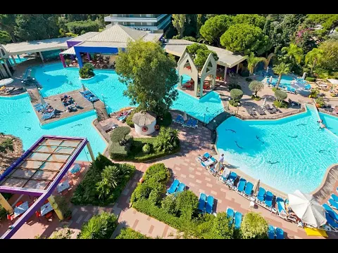 Außenpool des Dionysos Hotels mit umliegenden Gebäuden und Sonnenliegen.