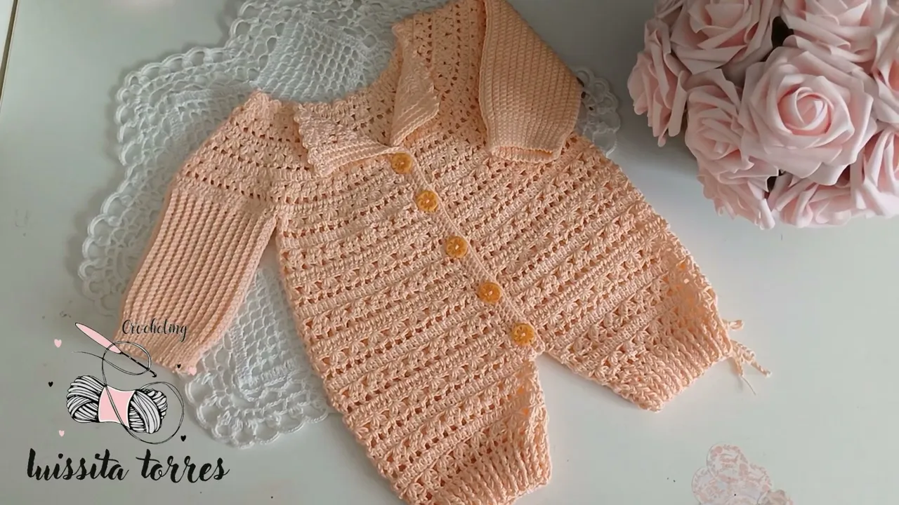 Enterizo de bebé a crochet color durazno, con cuerpo calado, mangas largas, cuello doblado y botones en el frente.