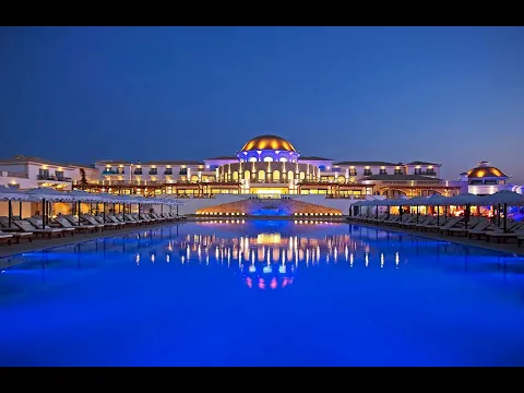 Außenpool mit Sonnenliegen und einem großen Hotelgebäude im Hintergrund.