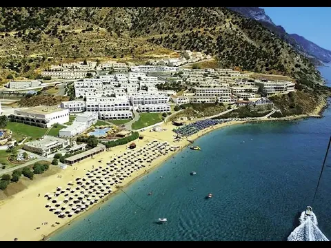 Luftaufnahme des Mitsis Summer Palace Beach Hotels mit vielen Gebäuden und einer langen Strandlinie.
