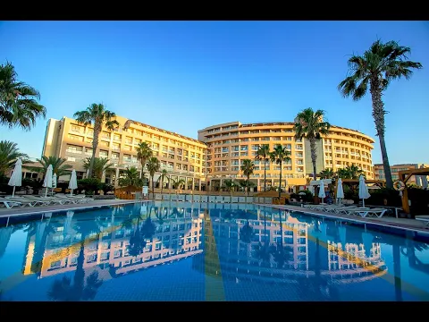 Die Außenansicht des Fame Residence Lara & Spa Hotels bei Nacht, mit beleuchteten Palmen und einem Pool.