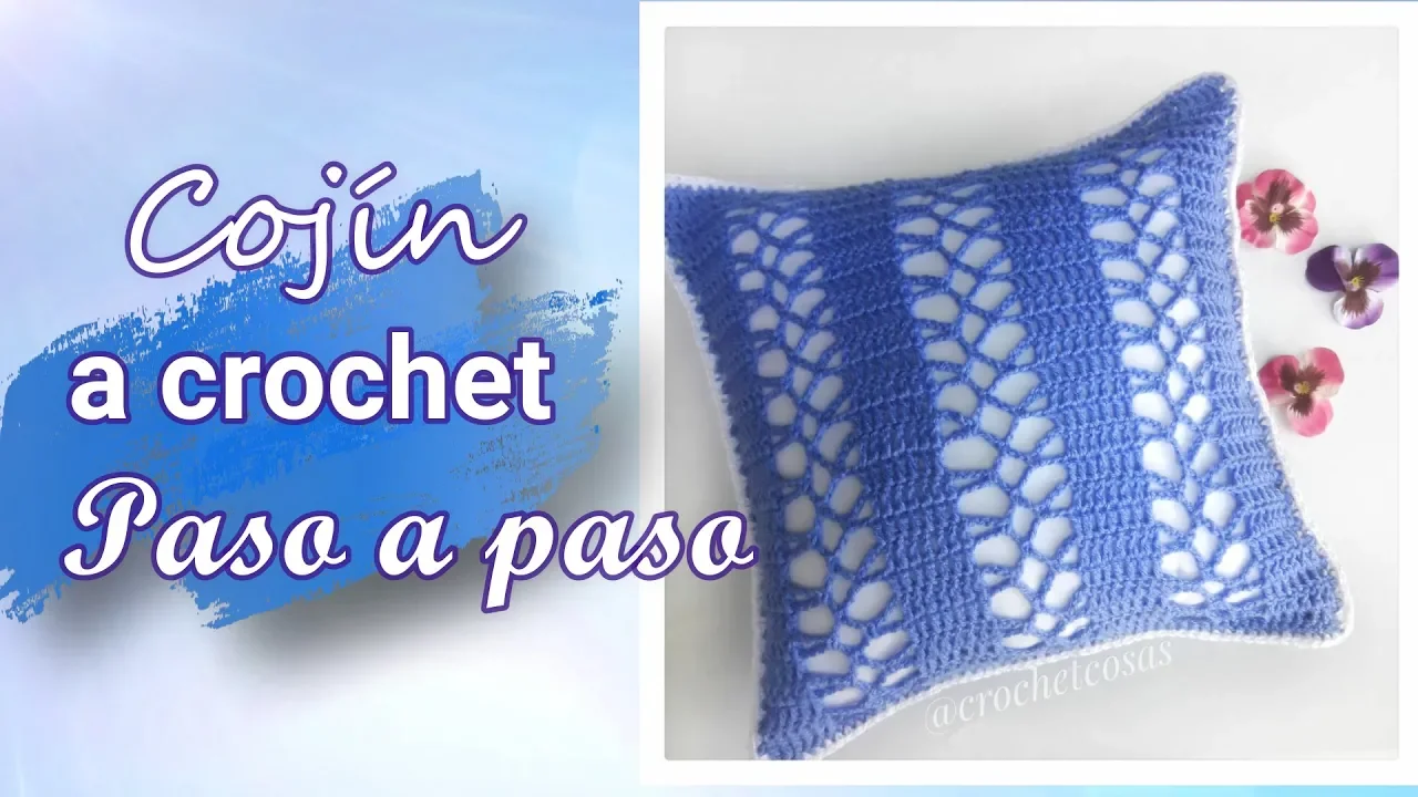 Cojín cuadrado azul a crochet con franjas tupidas y columnas caladas sobre una funda interior blanca.