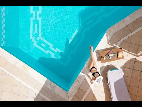 Die Vorderansicht des Petit Palais Hotels mit Eingangsbereich und Blumenbeeten davor.