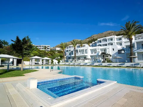 Außenbereich des Dimitra Beach Hotel & Suites mit Swimmingpool und Sonnenliegen.