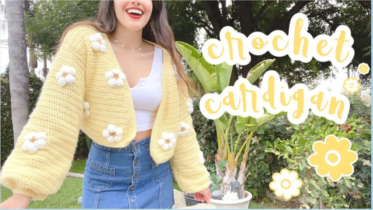 Cárdigan amarillo a crochet de manga larga, con flores blancas en relieve y centro amarillo.