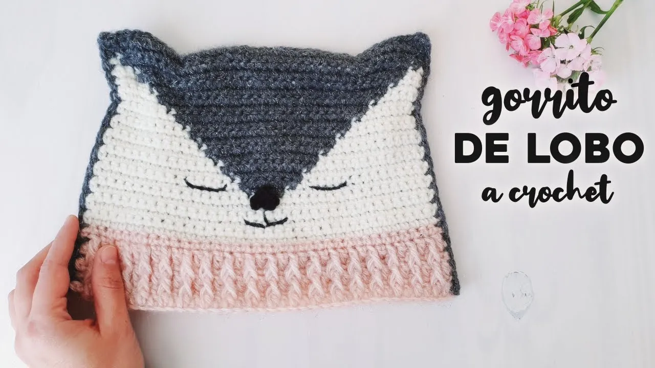 Gorro de lobito a crochet en gris, crudo y rosa, con orejas puntiagudas y rostro bordado.