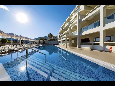 Außenansicht des Lindos White Hotel & Suites mit weißen Gebäuden, Balkonen und umgeben von Pflanzen und Blumen.