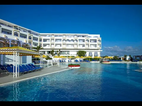 Außenpoolbereich des Serita Beach Hotels mit blauen Sonnenliegen und gelben Sonnenschirmen.