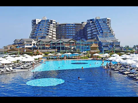 Poolbereich des Limak Lara De Luxe Hotel & Resort mit mehreren Liegestühlen und Sonnenschirmen.