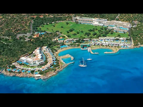 Luftaufnahme des Porto Elounda Golf & Spa Resorts mit Blick auf das Meer und mehrere Gebäude.