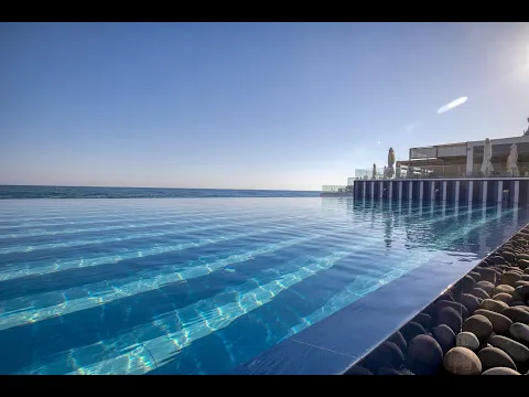 Pool-Terrasse des I Resort Beach Hotel & Spa mit weißen Sonnenschirmen und Liegen.