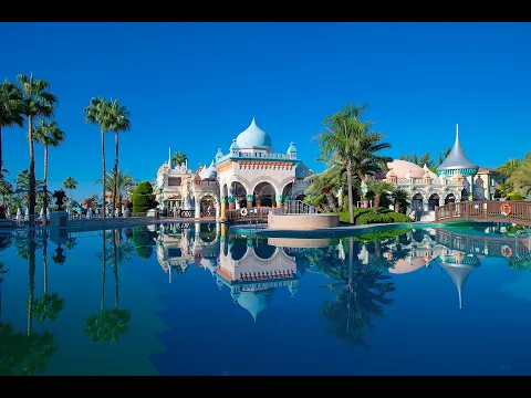 Pool im Kamelya Aishen K Club Hotel bei Nacht mit Gebäude und Palmen im Hintergrund.