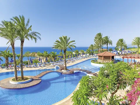 Außenansicht des Rodos Princess Beach Hotels mit mehreren Schwimmbädern und grünen Rasen.