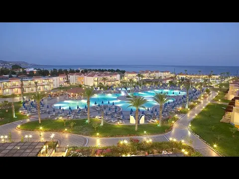 Abendansicht des Lindos Princess Beach Hotels mit Pool, Sonnenliegen und Palmen.