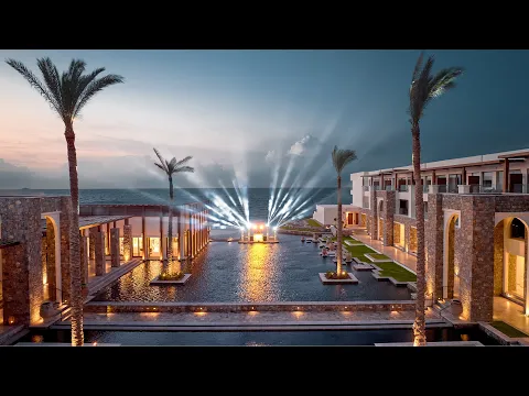 Eingangsbereich des Amirandes Grecotel Boutique Resorts mit hohen Palmen und einem Wasserbecken.