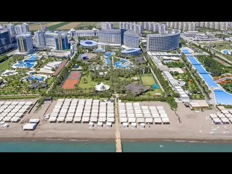 Außenansicht des Royal Wings Resorts mit mehreren Swimmingpools, Sonnenschirmen und tropischen Bäumen.