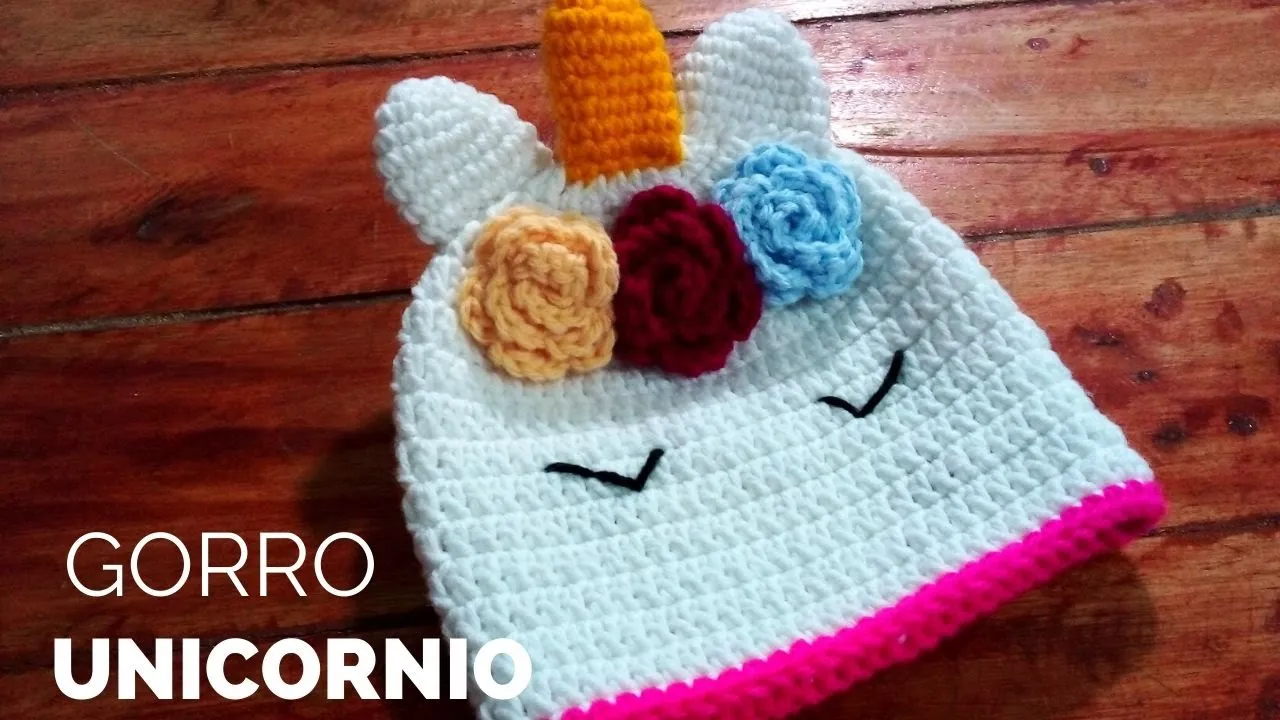 Gorro de unicornio blanco a crochet con cuerno amarillo, flores de colores y ojos bordados