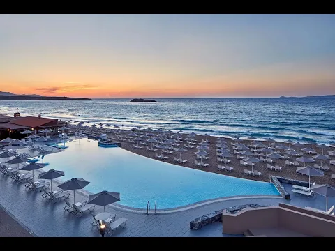 Eingang des Aks Minoa Palace Hotels mit Palmen und blauem Himmel