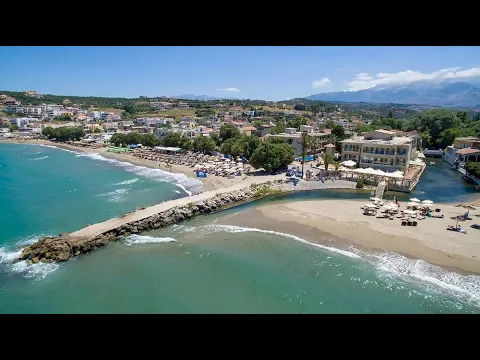 Luftaufnahme des Kalyves Beach Hotels mit Strand, Gebäuden und umliegender Landschaft.