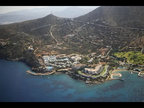Luftaufnahme des Elounda Village Resort & Spa mit mehreren Pools und Gebäuden am Meer.