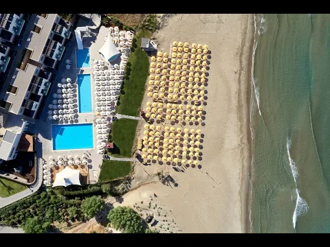 Eingang des Atlantica Akti Zeus Hotels mit zwei Palmen vor einem blauen Himmel