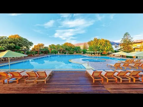 Außenansicht des Apollonia Beach Resort & Spa mit grünen Kletterpflanzen und roten Blumen.