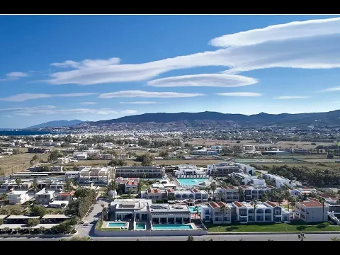 Außenbereich des Pelagos Suites Hotel & Spa mit Swimmingpool und Sonnenliegen.