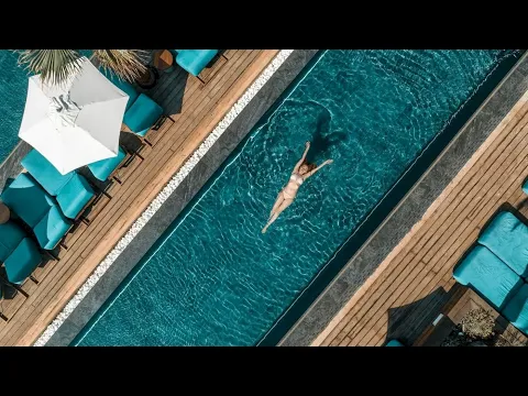 Außenansicht des Mitsis Rinela Beach Hotels bei Nacht mit Beleuchtung und Palmen.