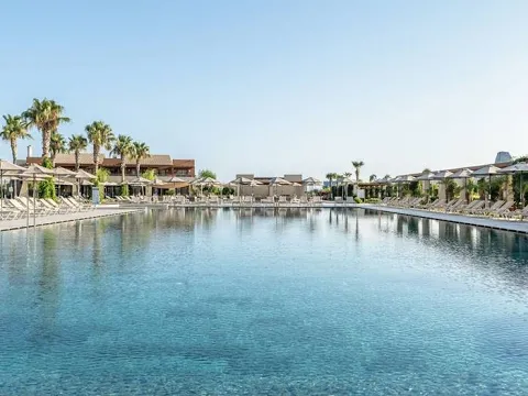 Außenbereich des Astir Odysseus Kos Resort & Spa mit Swimmingpool und Sonnenliegen.