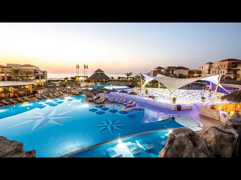 Luftaufnahme des Infinity-Pools des Atlantica Caldera Palace Hotels mit Loungebereich und Sonnenschirmen.