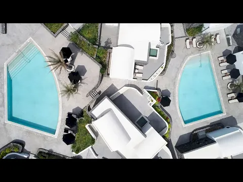 Außenpool des Santo Pure Oia Suites Hotels mit weißen Liegen und Sonnenschirmen