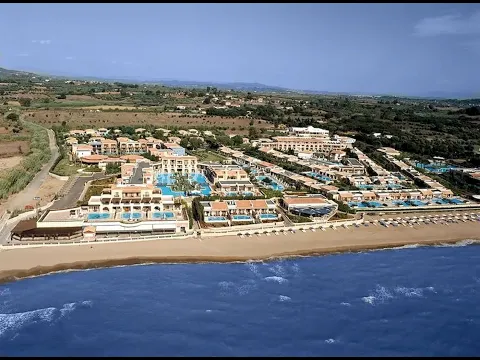 Luftaufnahme des Mitsis Royal Mare Thalasso & Spa Resorts mit mehreren Swimmingpools und einer langen Strandlinie.
