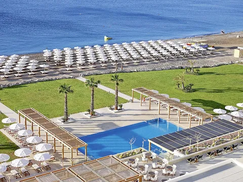 Abendstimmung am Swimmingpool des Mitsis Alila Resort & Spa mit Palmen und Sonnenuntergang